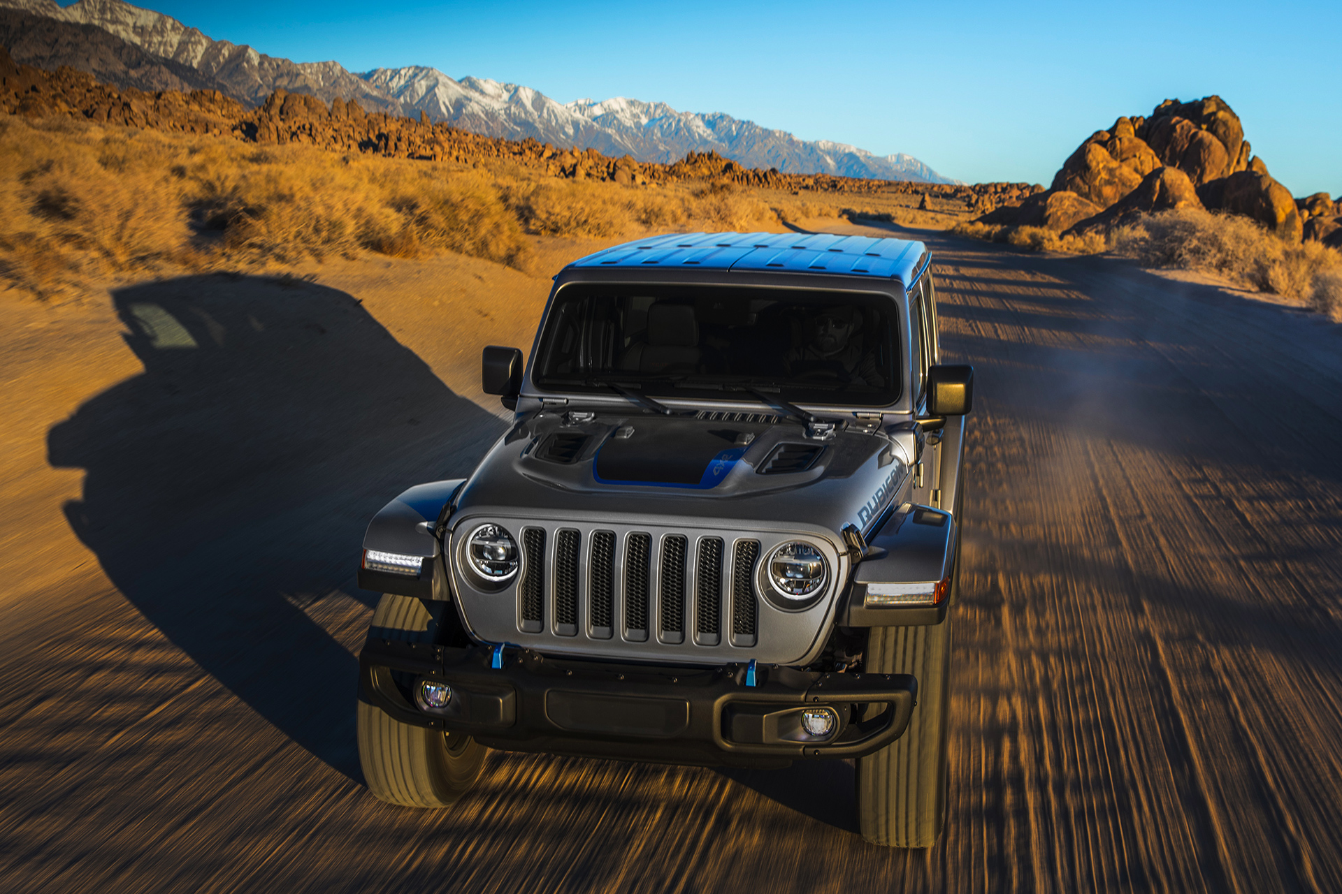 vue avant du Jeep Wrangler Rubicon 4xe 2021 gris métallisé conduisant sur une route dans un désert